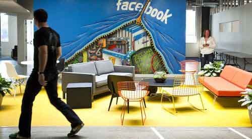 Una pared donde se lee Facebook y hay unos sillones delante